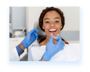 A black woman sitting in dental chair a professional trying to insert invisalign in her mouth