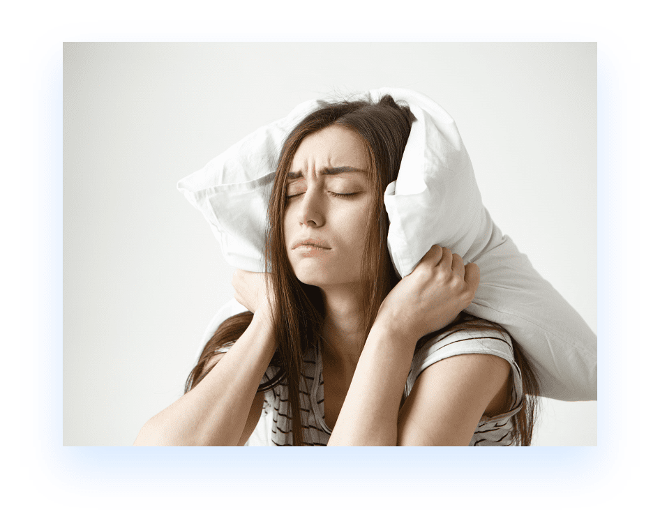 woman in bed with pillow covering her head
