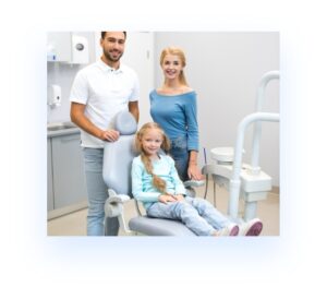 A child in the dental chair with her parents standing next to her
